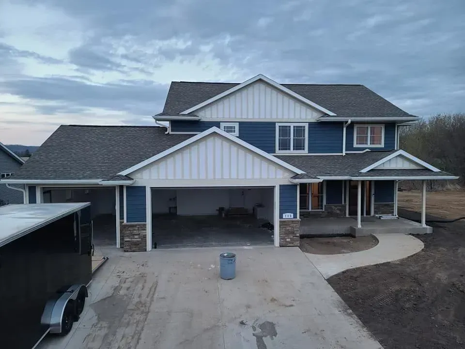 A two-story blue house with white trim, a stone-accented garage.