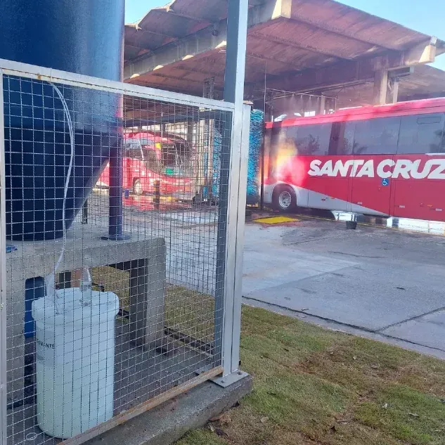 Um ônibus vermelho de Santa Cruz está estacionado em frente a uma cerca