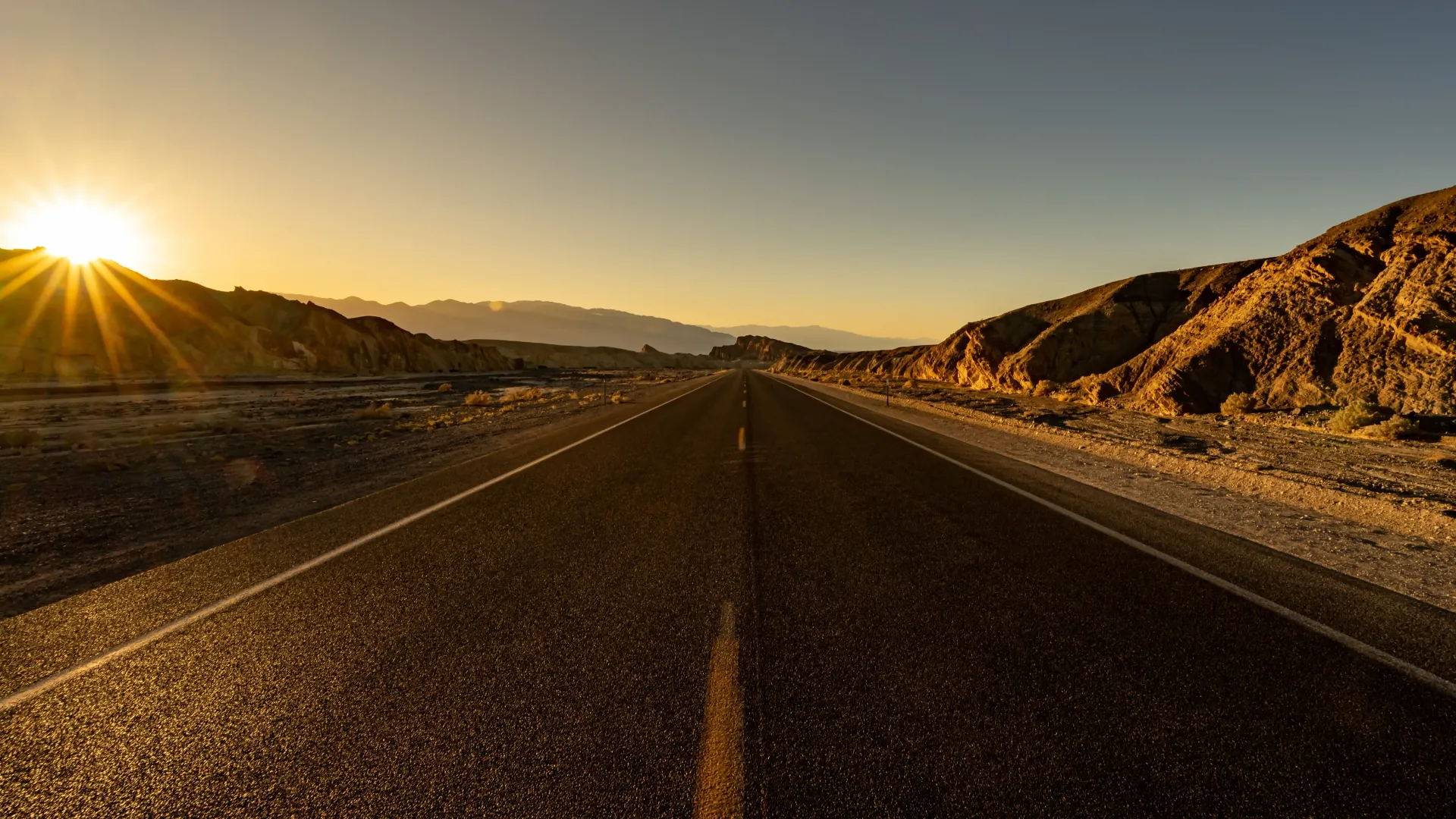 O sol está se pondo sobre uma estrada deserta.