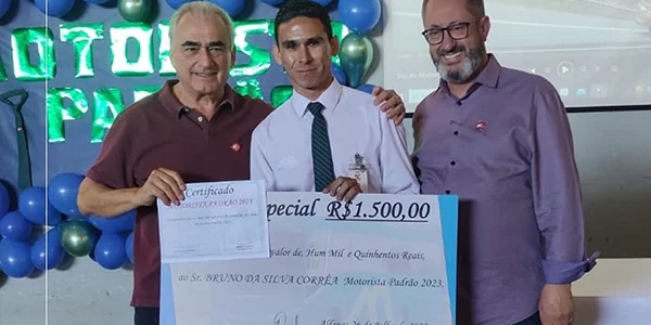 Três homens estão parados um ao lado do outro segurando um cheque grande.