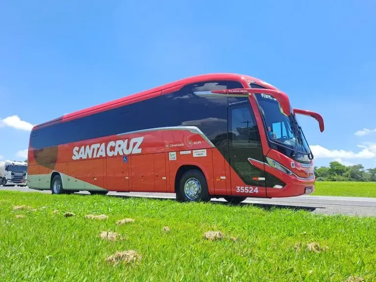 Um ônibus vermelho de santa cruz está estacionado na beira da estrada.