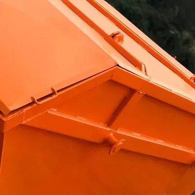 Um close de uma lixeira laranja com a tampa aberta