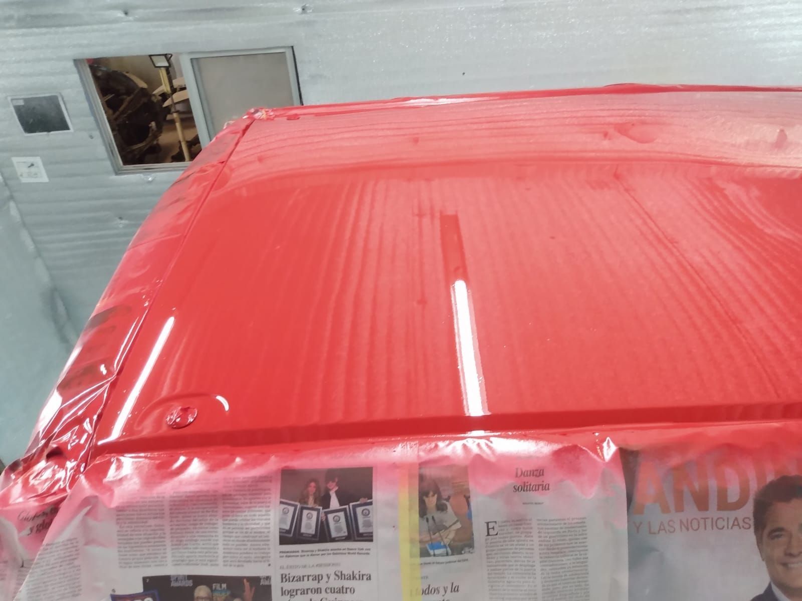 Techo de vehículo rojo recién pintado en garaje.