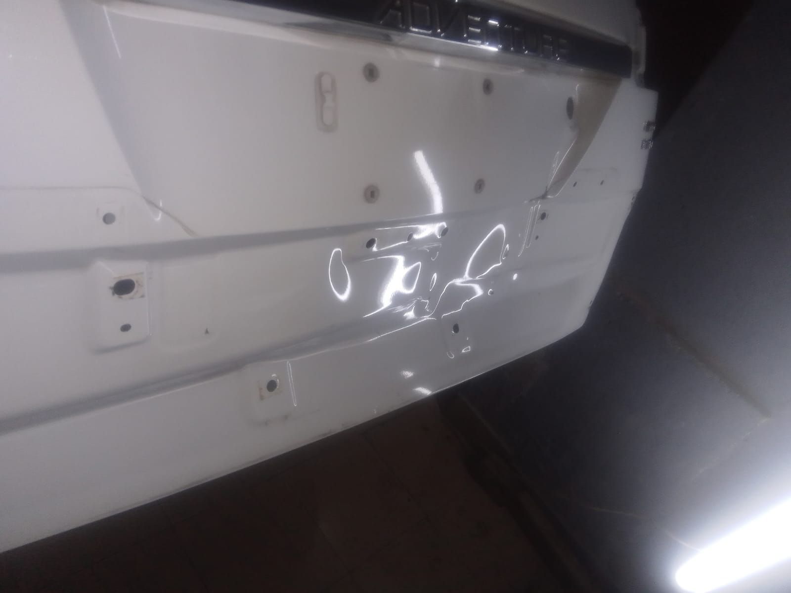 Parachoques de coche blanco con varias abolladuras.