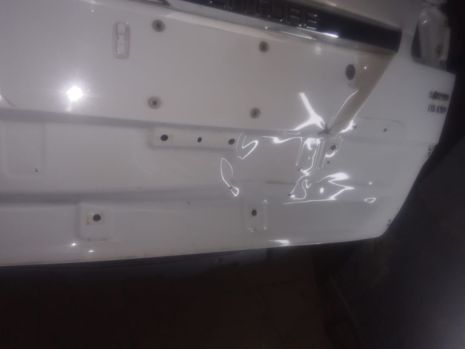 Parachoques de coche blanco con una abolladura.