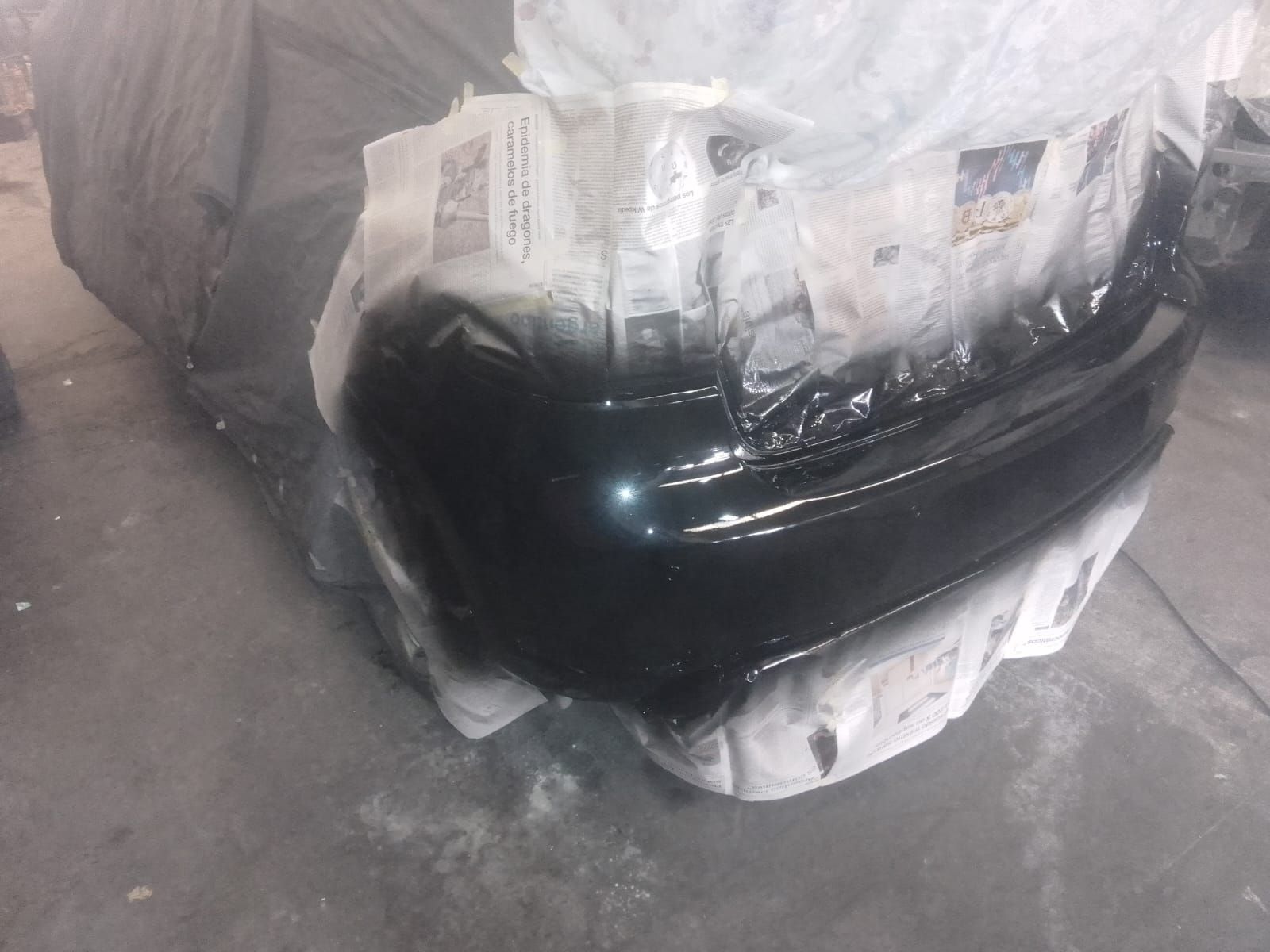 Parachoques de coche negro pintado con aerosol en un garaje.