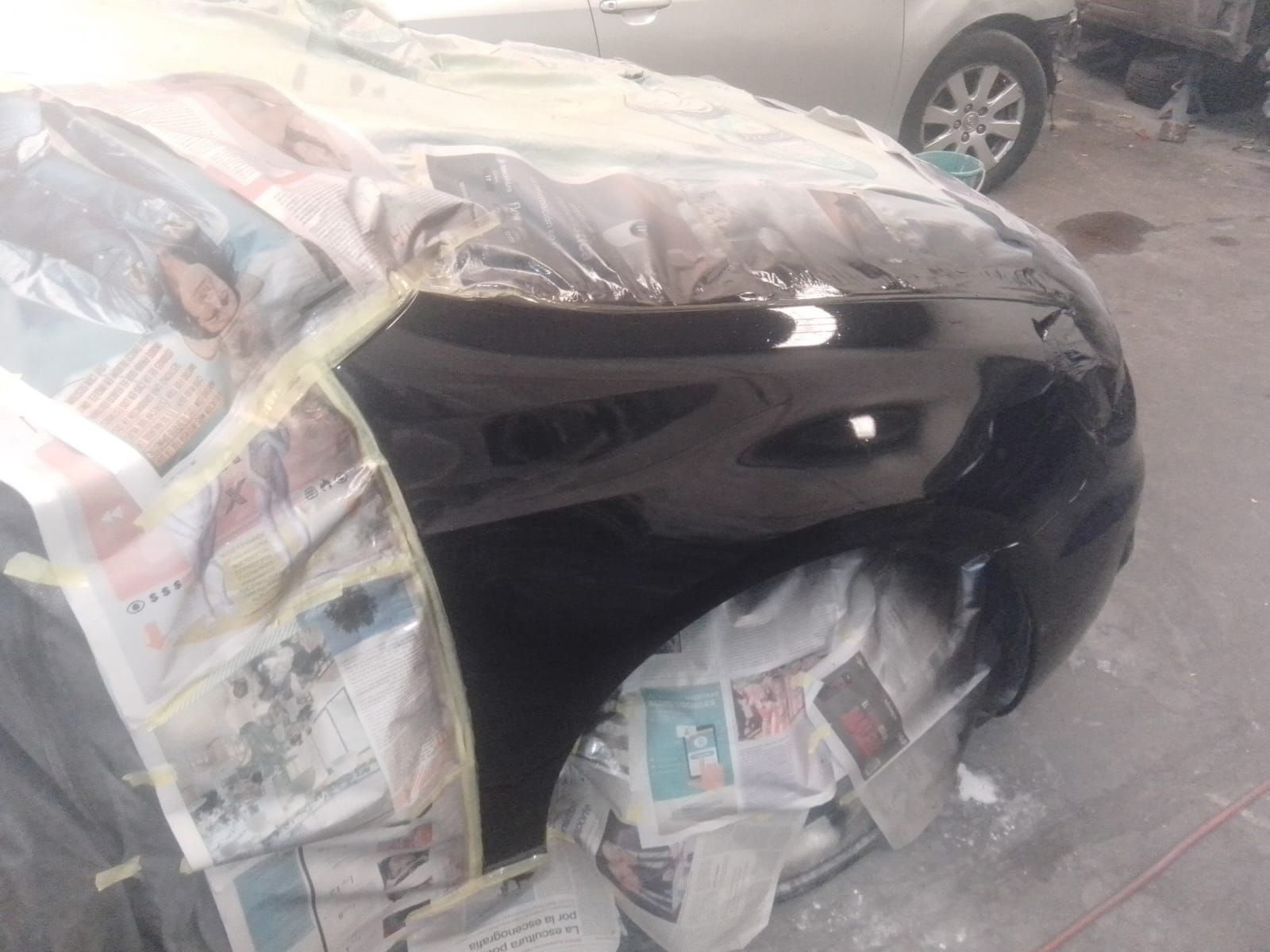Guardabarros de coche pintado de negro, enmascarado con papel y plástico.