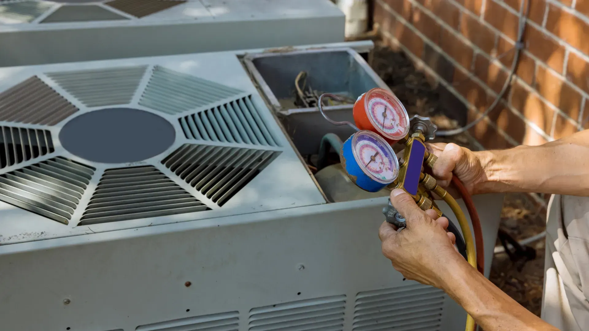 A technician checking an AC unit's pressure with gauges in an outdoor setting.