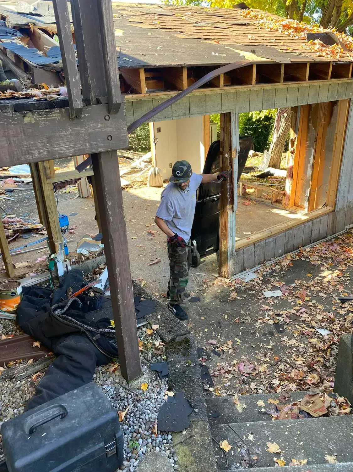 A man is standing in front of a house that is being demolished.