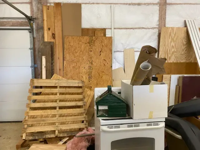 A white stove is stacked on top of a wooden pallet in a garage.