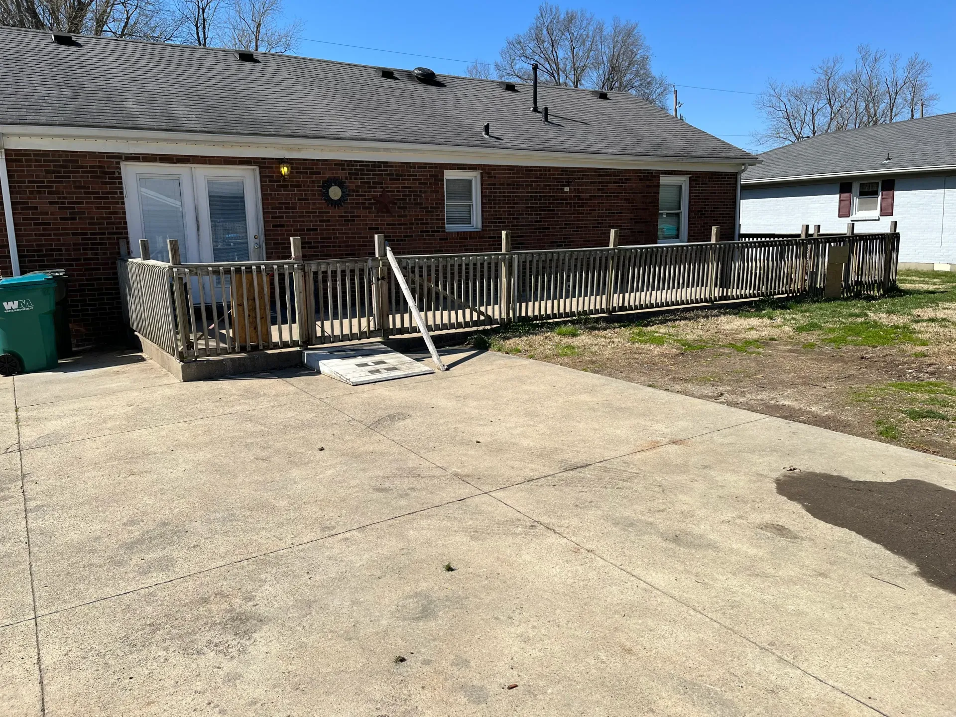 A brick house with a wooden deck and a concrete driveway.