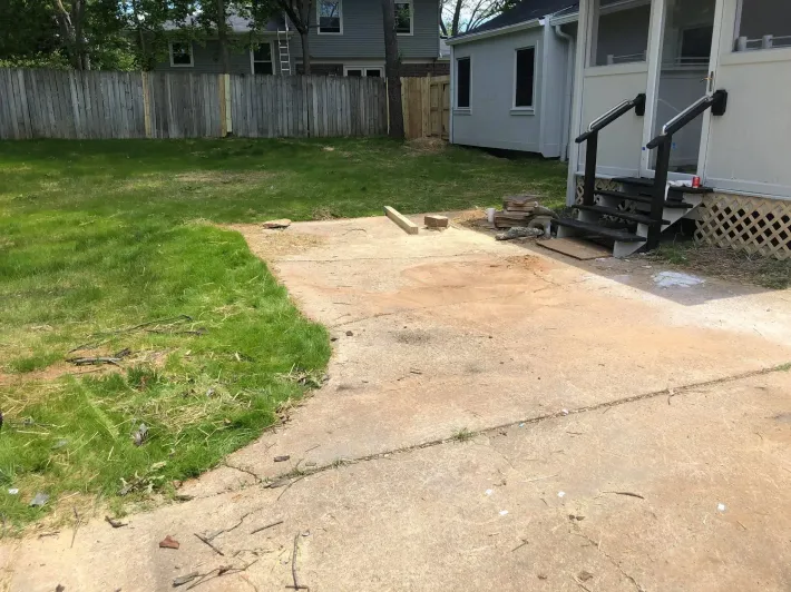 A concrete driveway leading to a house with a fence in the background.