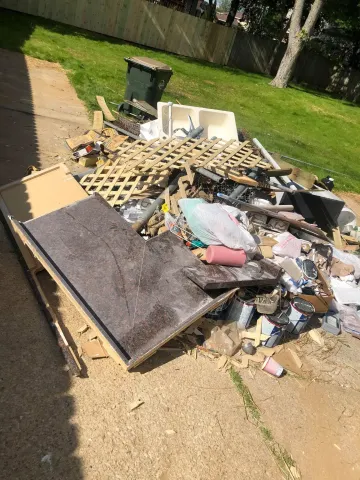 A pile of trash is sitting on the sidewalk next to a fence.