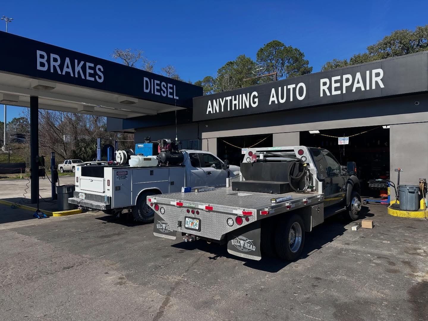 Auto repair shop with two tow trucks parked under signs for brakes and diesel. | Anything Auto Repair
