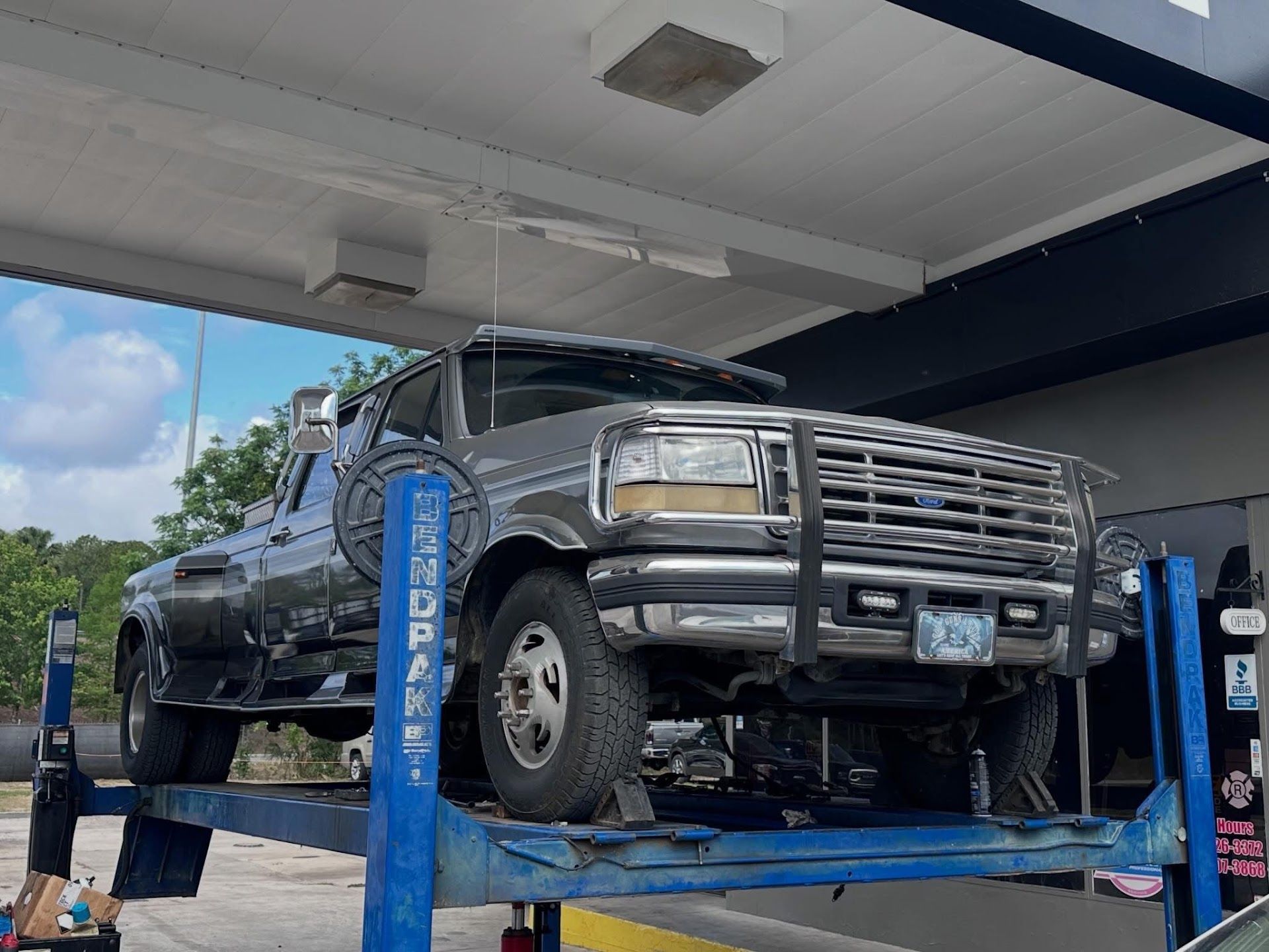 Black pickup truck on a blue lift inside a garage, viewed from the front-left side | Anything Auto Repair