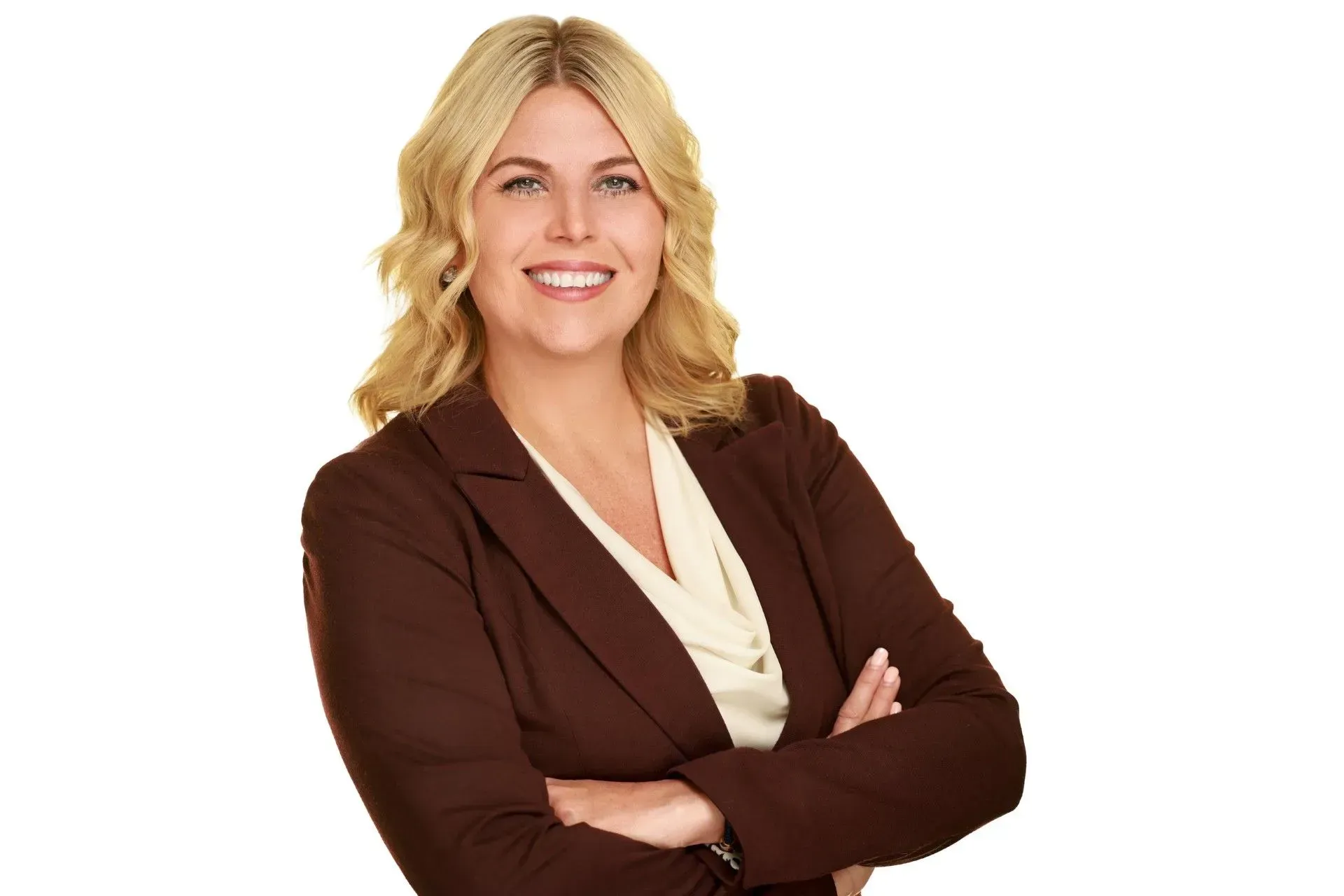 Woman in brown blazer with arms crossed, smiling.