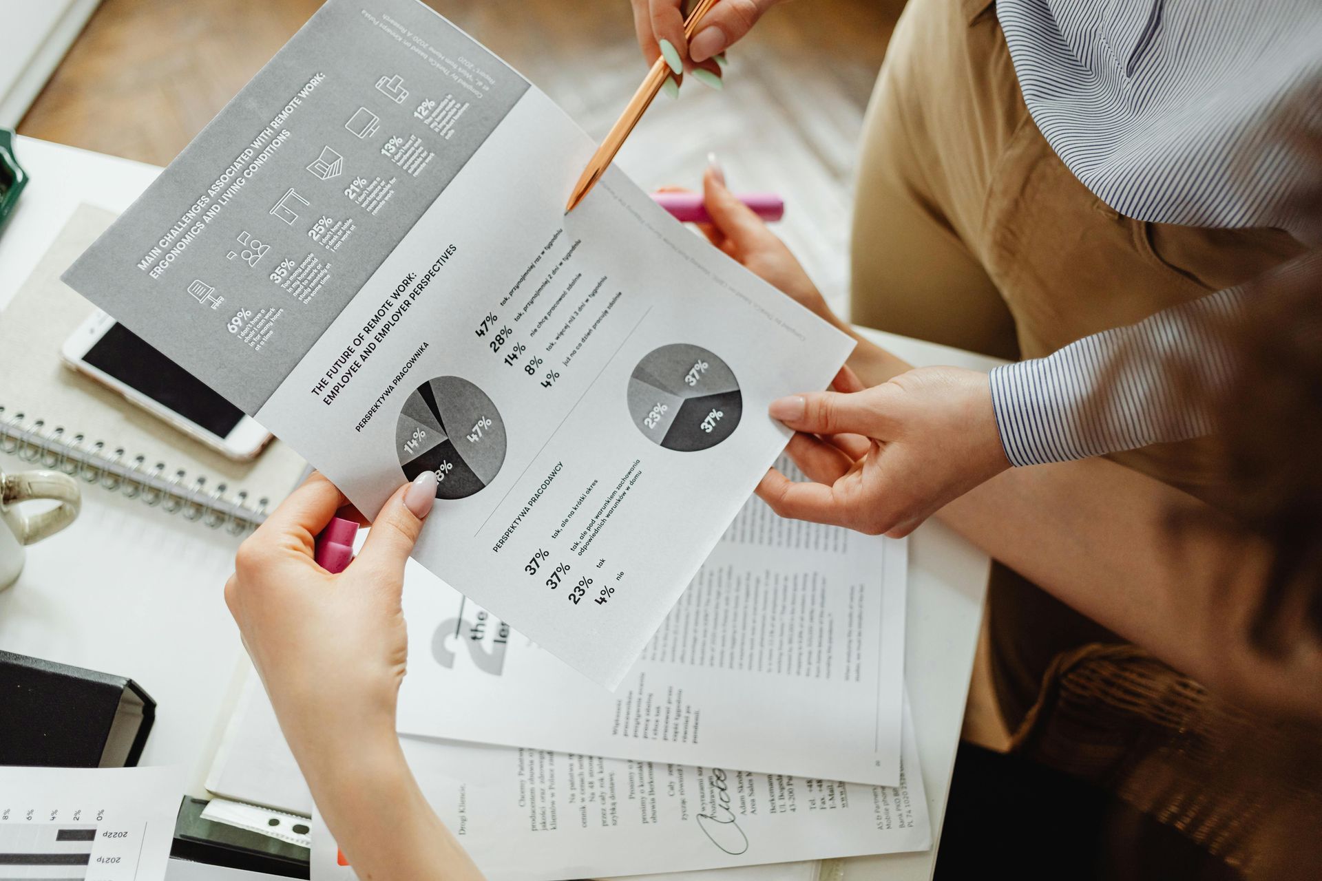 Two people reviewing reports with pie charts, pencil pointing, office setting.