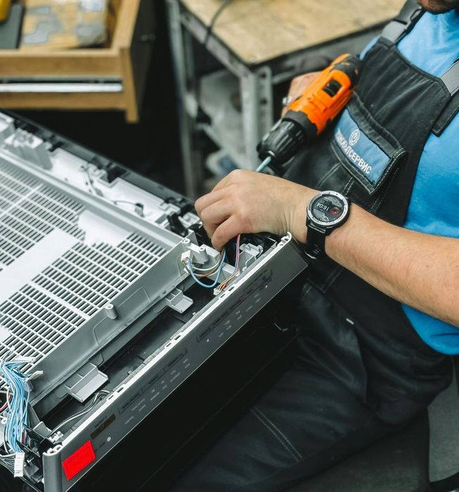A man wearing a watch is working on a dishwasher