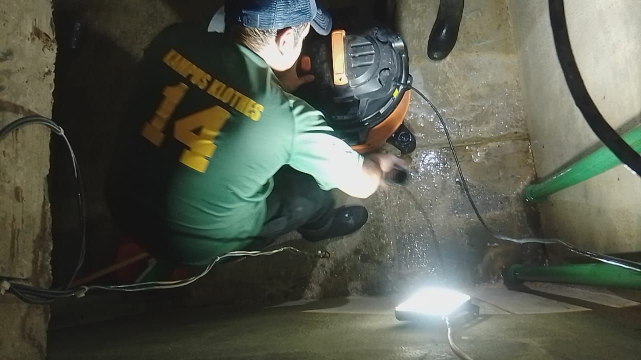 Dos personas inspeccionan el agua en un recinto de hormigón. Una de ellas lleva una camiseta verde con la etiqueta