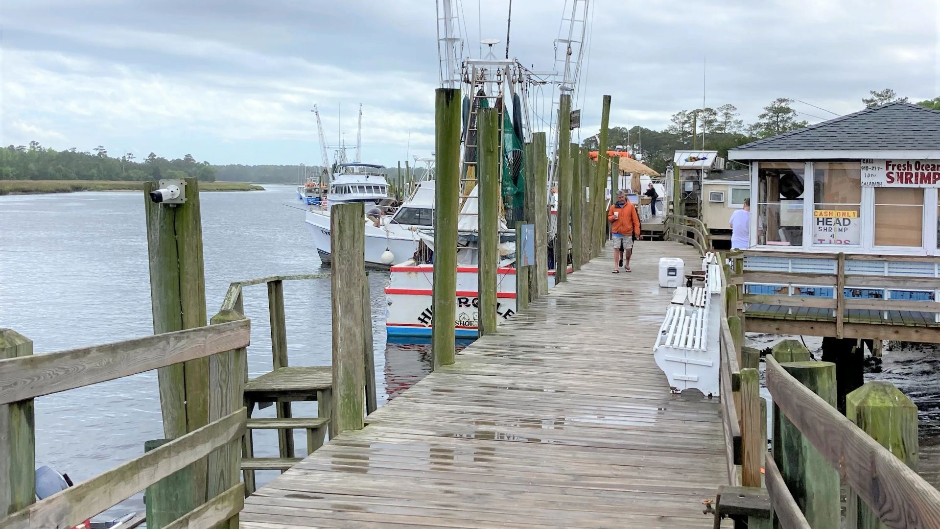 A wooden dock with boats docked at the end of it