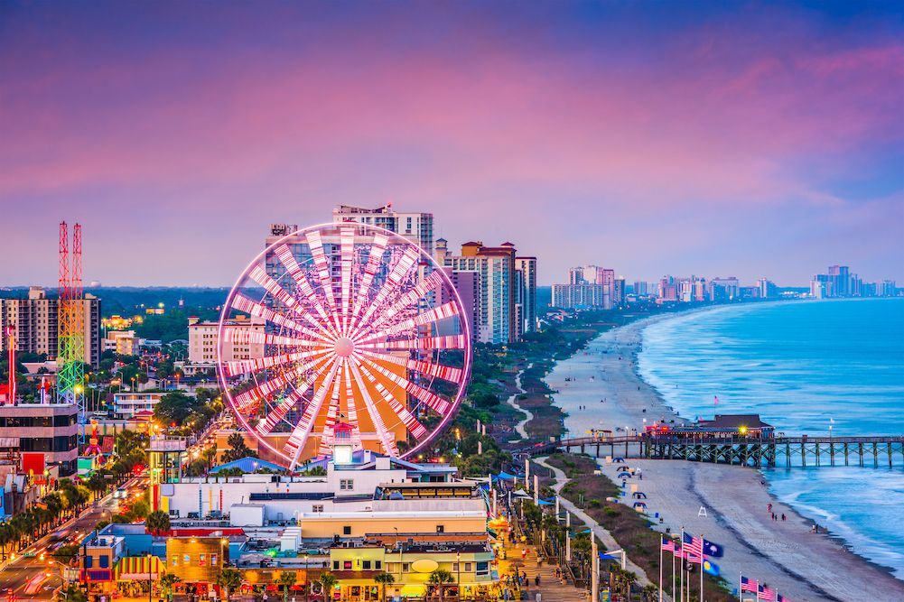 An aerial view of a city with a ferris wheel in the foreground.