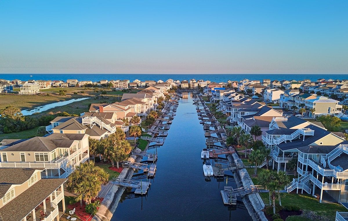 An aerial view of a residential area along a canal with boats docked.