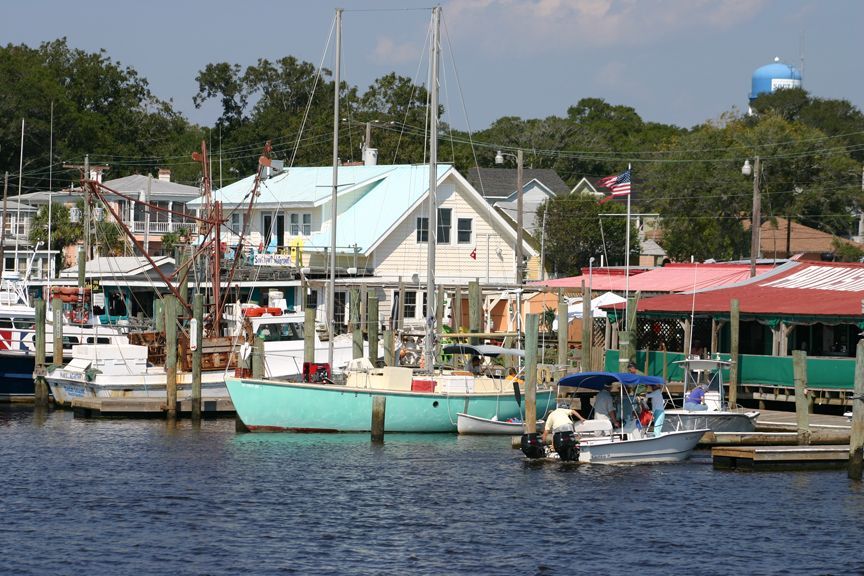 Several boats are docked in a harbor with a water tower in the background
