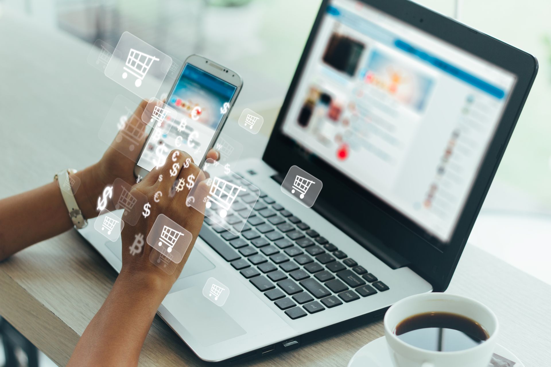 A person is sitting at a table using a laptop and a cell phone.