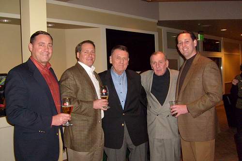A group of men are posing for a picture while holding wine glasses.