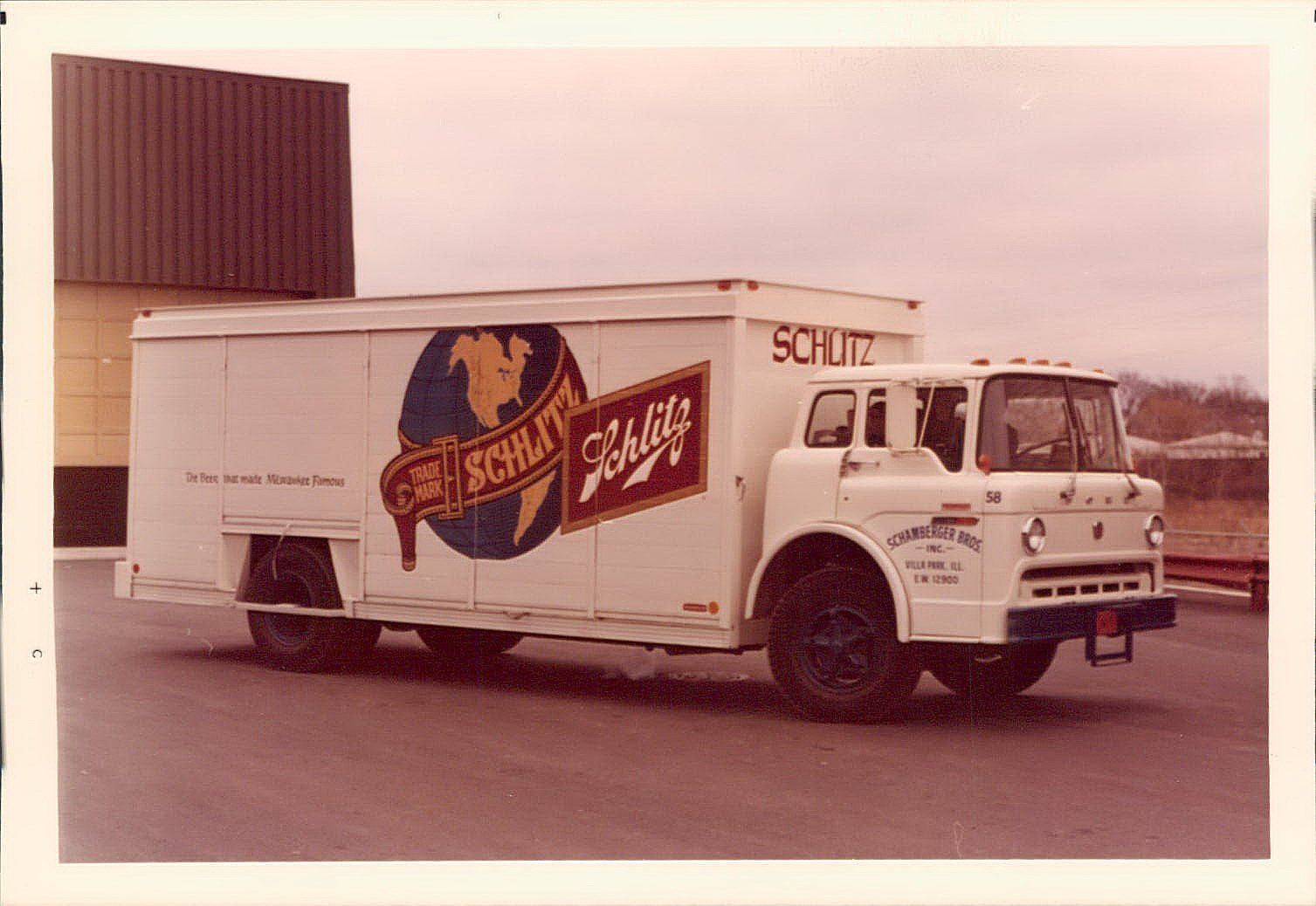 A white truck with the word scout on the side is parked in front of a building.