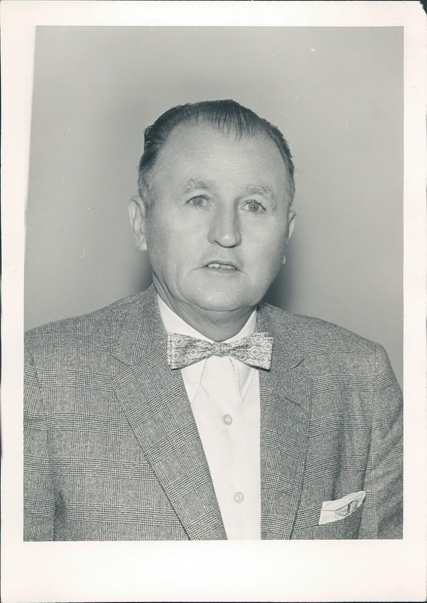 A black and white photo of a man in a suit and bow tie.