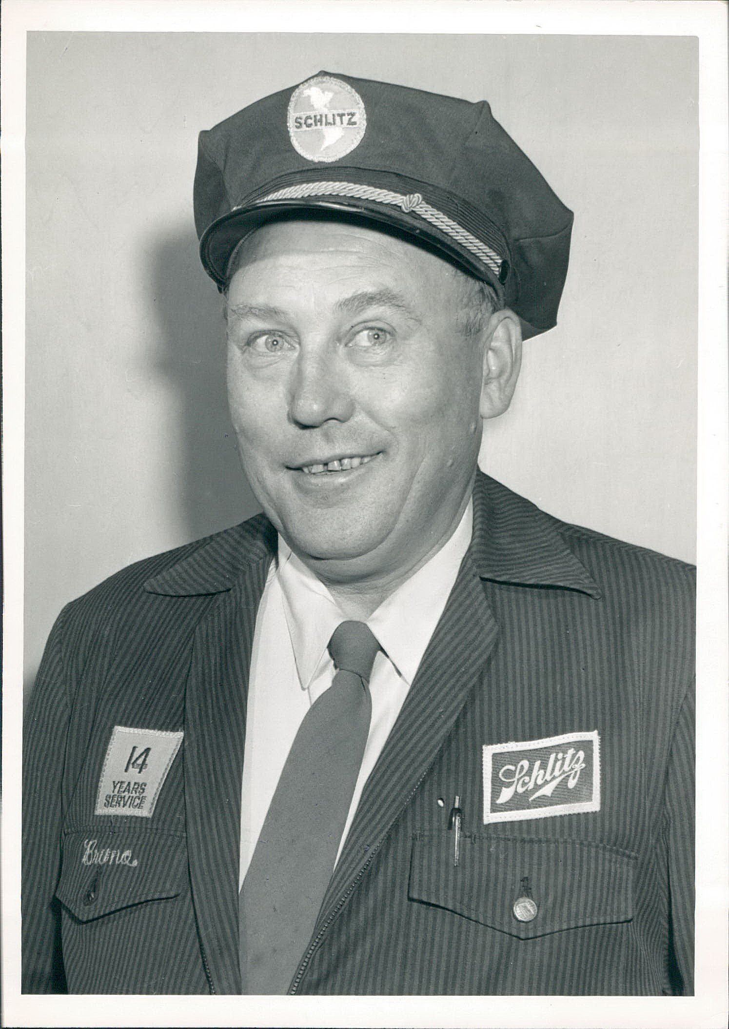 A black and white photo of a man wearing a hat and tie