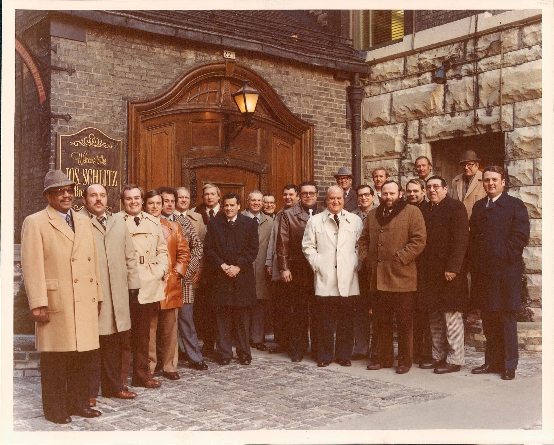 A group of men are posing for a picture in front of a sign that says postur