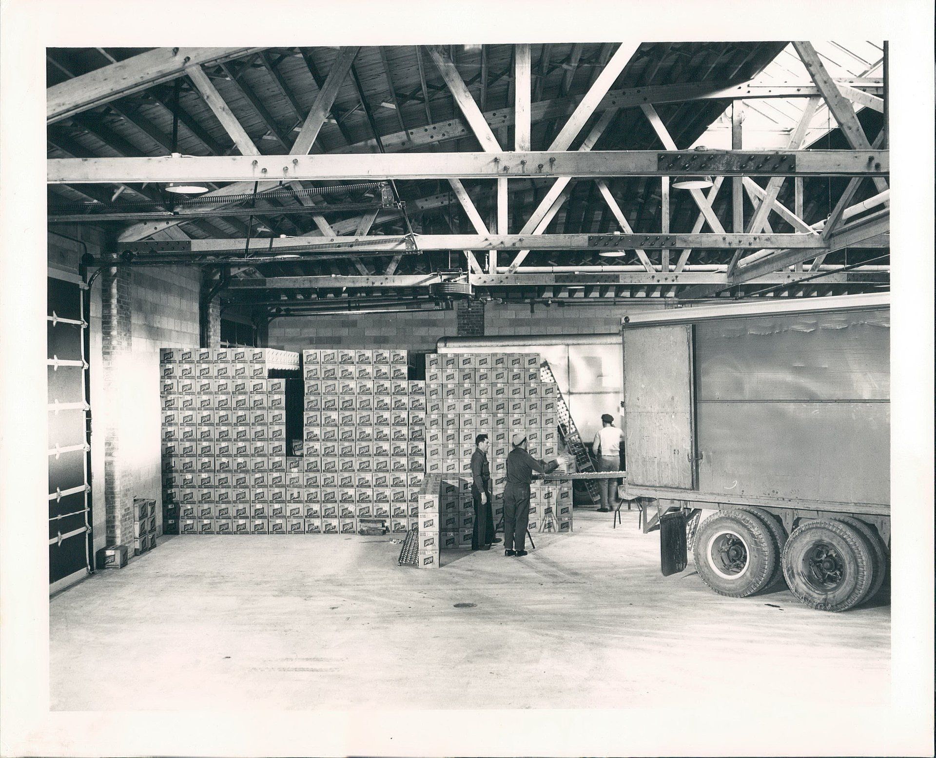 A black and white photo of a warehouse with boxes and tires