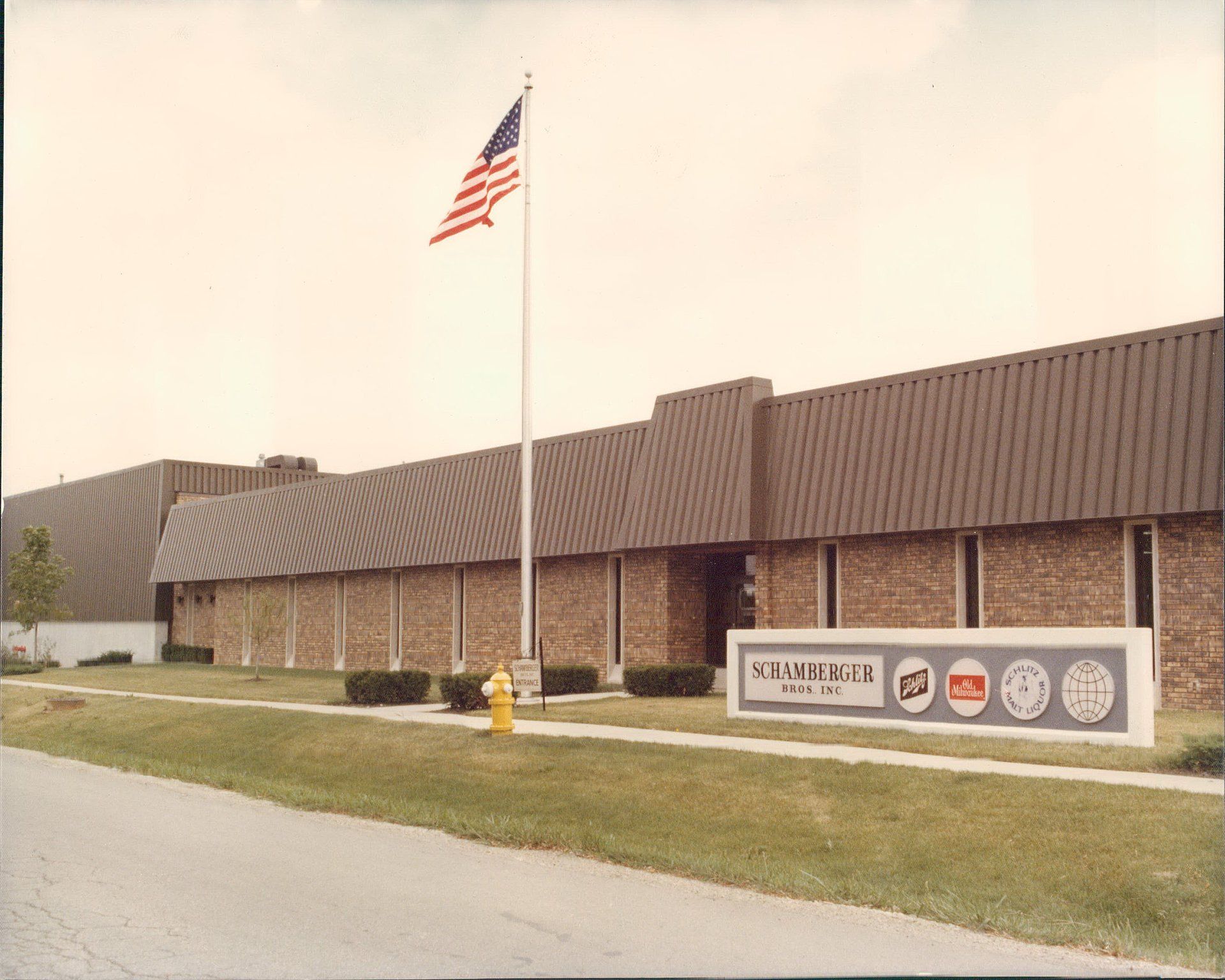 An american flag is flying in front of a building that says sandwich