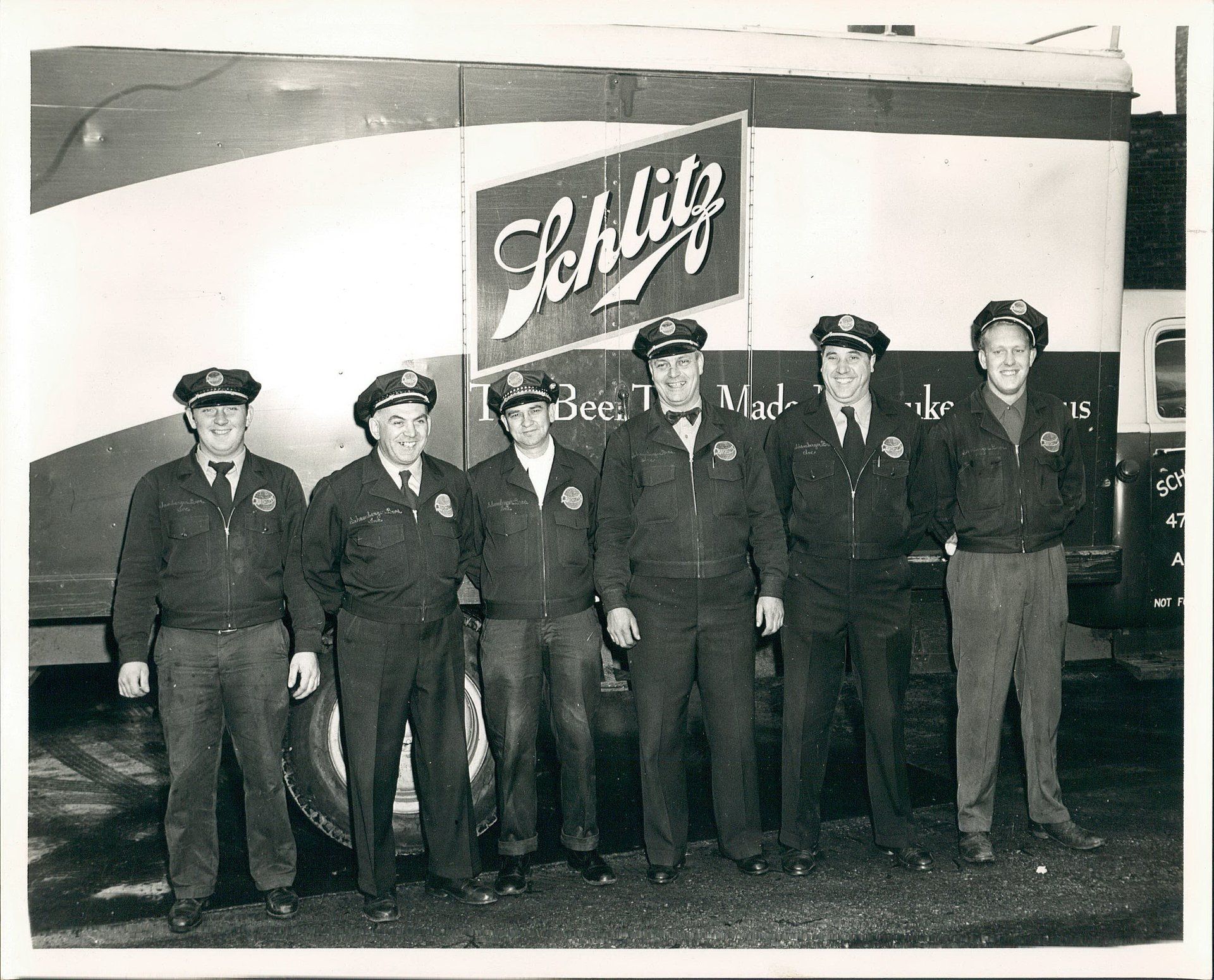 A group of men are posing in front of a truck that says schlig