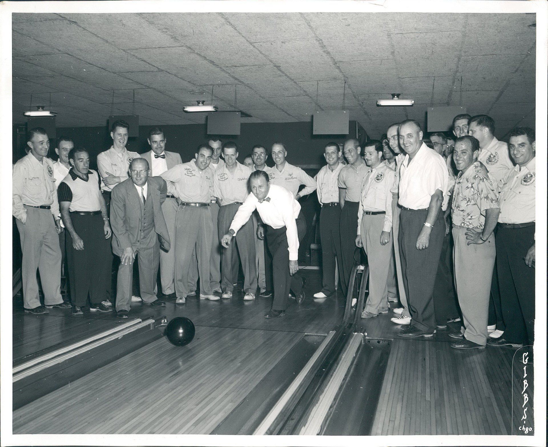 A group of men are standing around a bowling alley