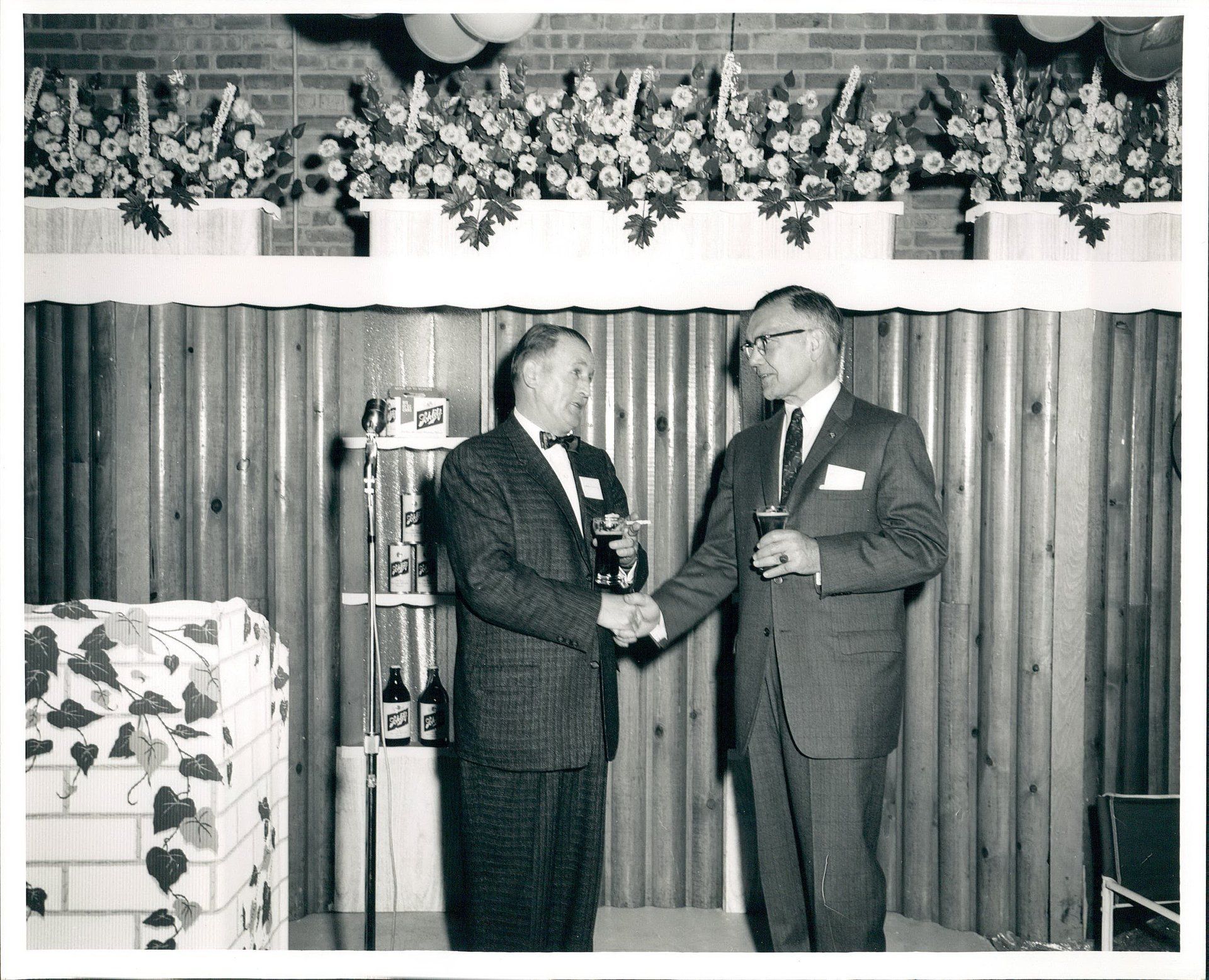 Two men shaking hands in front of a wooden wall