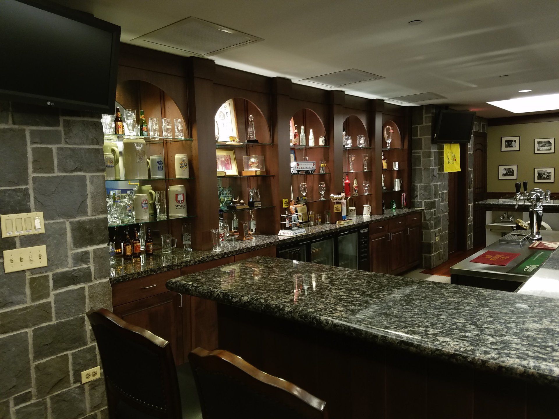A bar with bottles on shelves and a tv on the wall