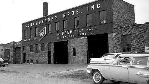 A black and white photo of a car parked in front of a brick building.