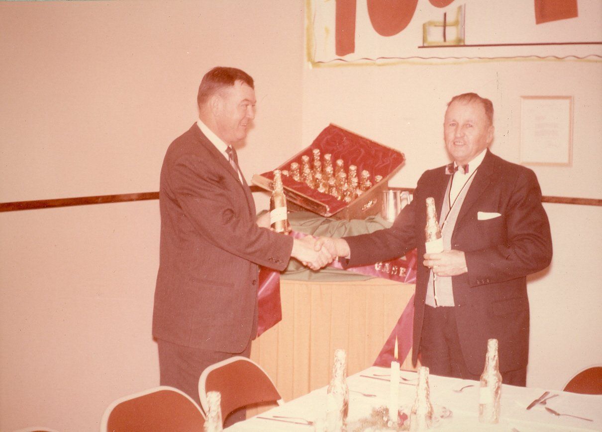 Two men shaking hands in front of a chess board