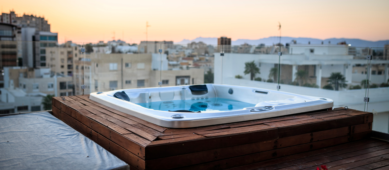 A hot tub is sitting on top of a wooden platform on the roof of a building.