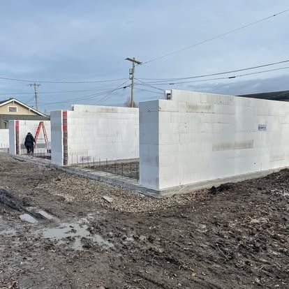 A construction site showing white insulating concrete form (ICF) blocks being assembled into wall structures on a lot.