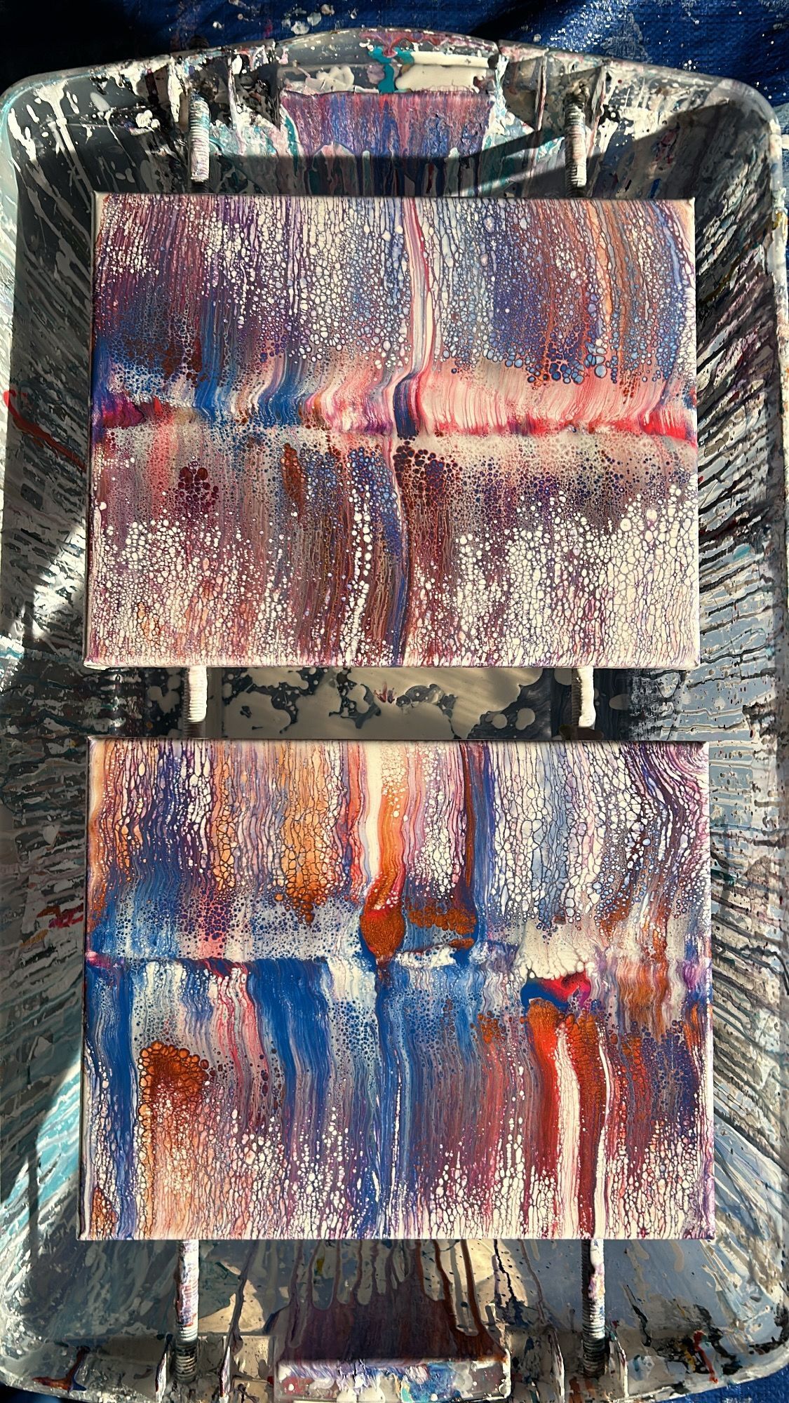 A close up of an acrylic flow painting on a tray on a table.