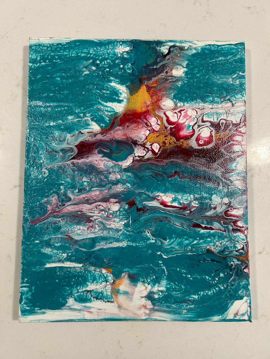 Abstract acrylic pour painting with turquoise, red, white, and gold colors.