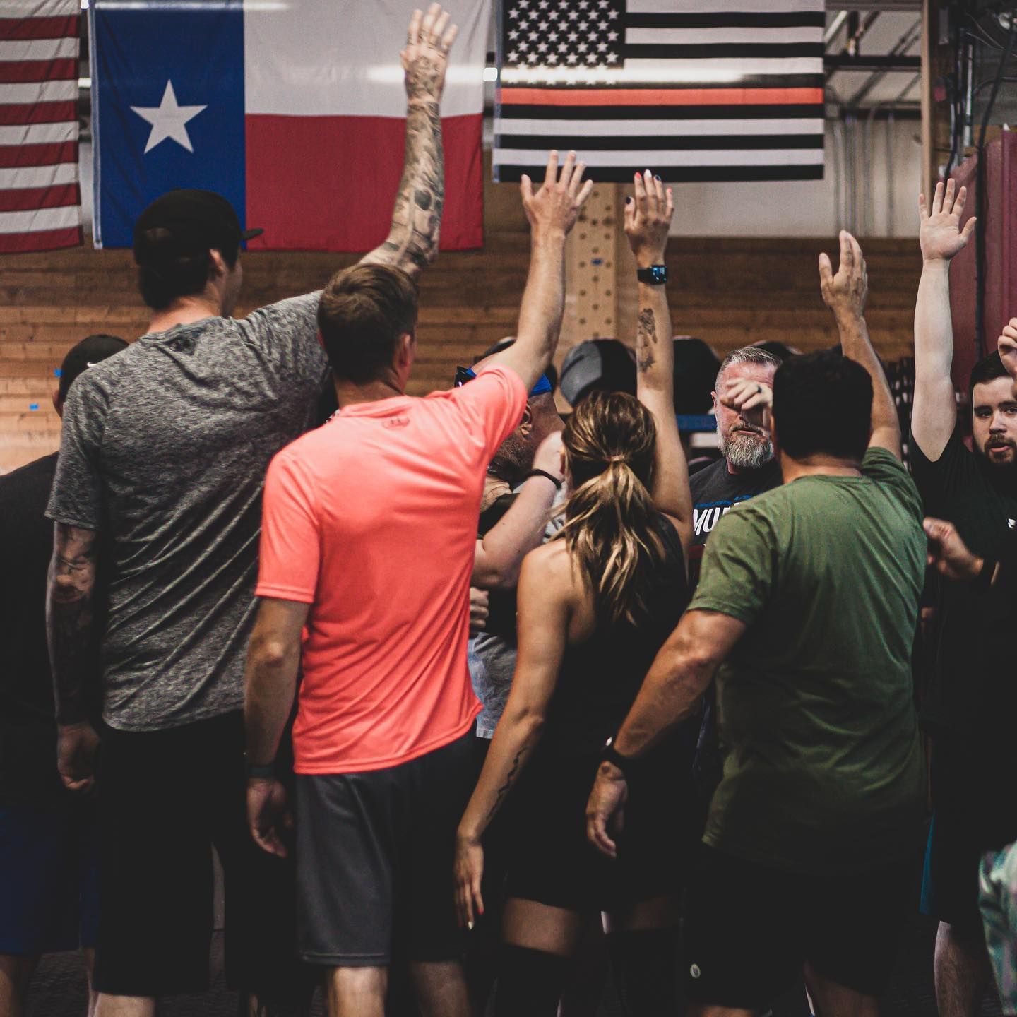 A group of people are raising their hands in the air in front of an american flag.