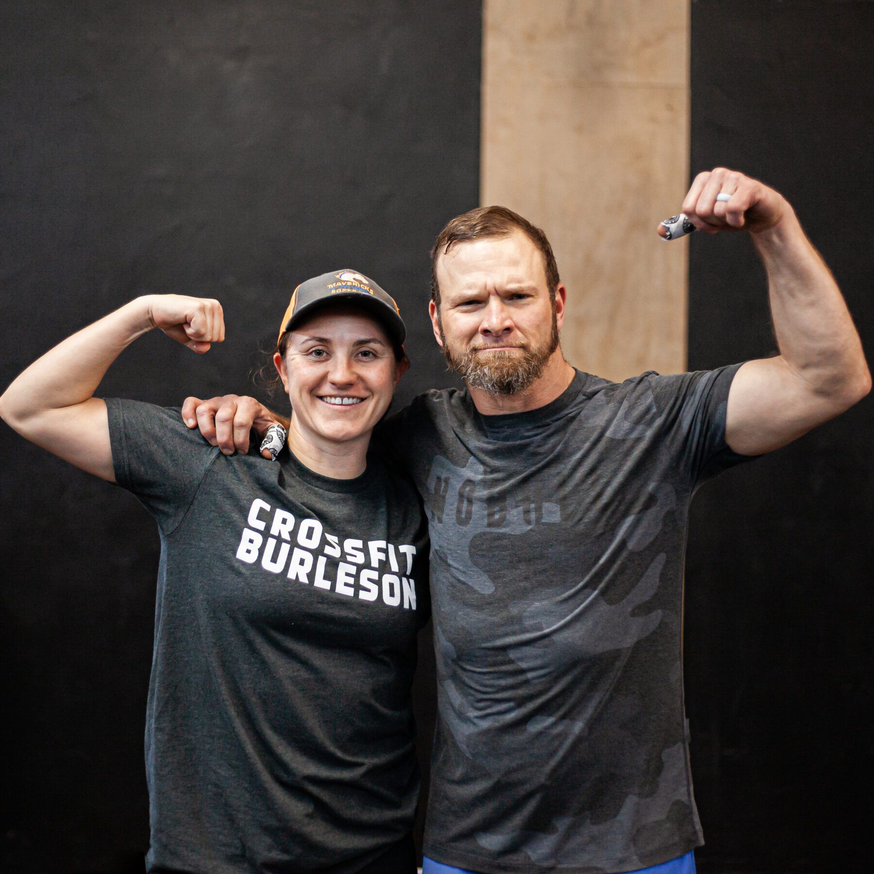 A man and a woman are posing for a picture and the woman is wearing a crossfit burleson shirt