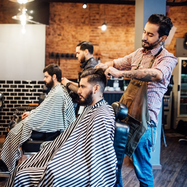 A man is getting his hair cut by a barber in a barber shop.