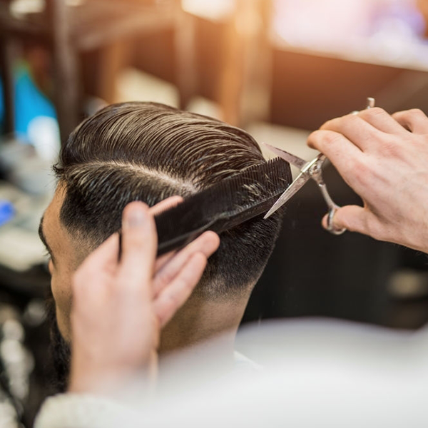 A man is getting his hair cut by a barber.