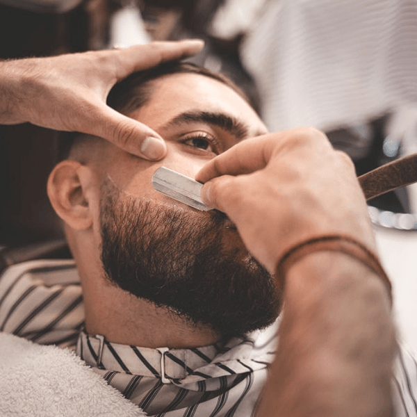 A man is getting his beard shaved by a barber